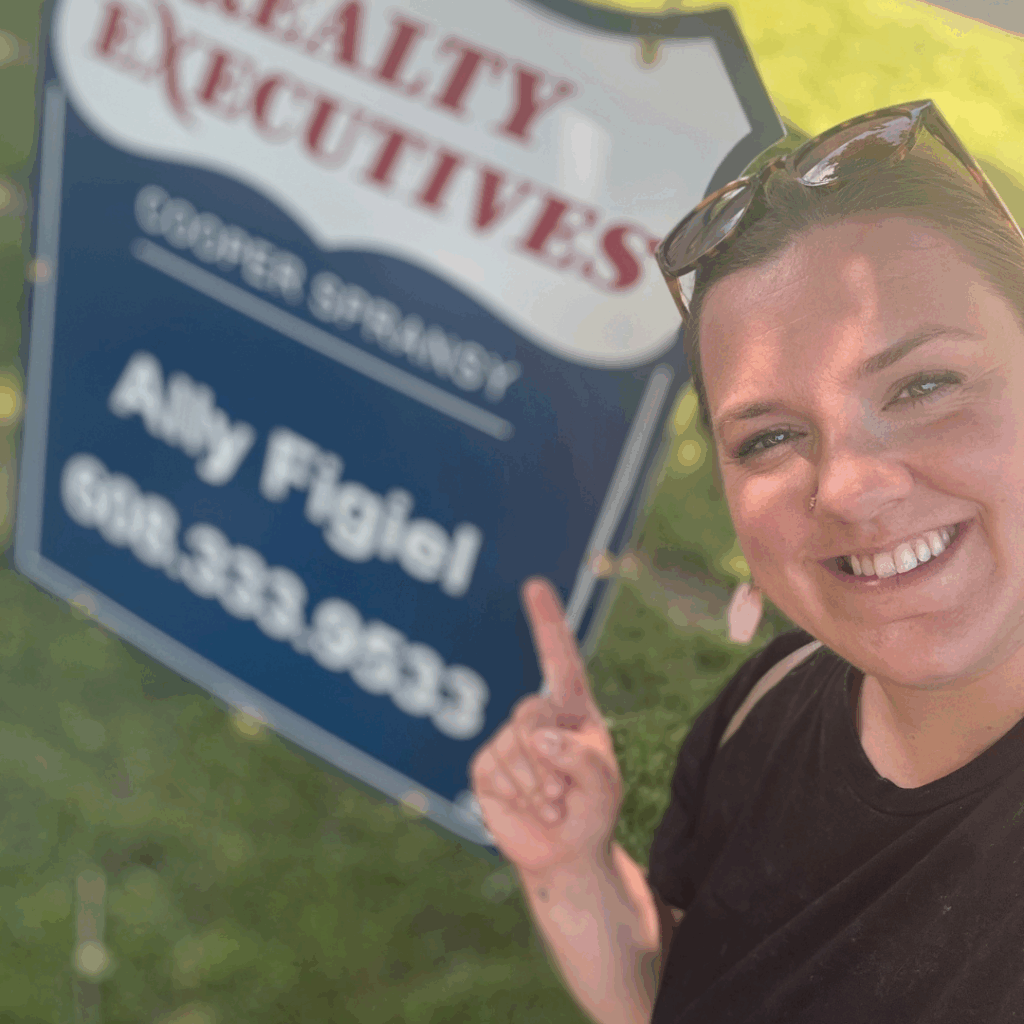 Ally Figiel smiling and pointing at her Realty Executives Cooper Spransy real estate sign in Madison WI