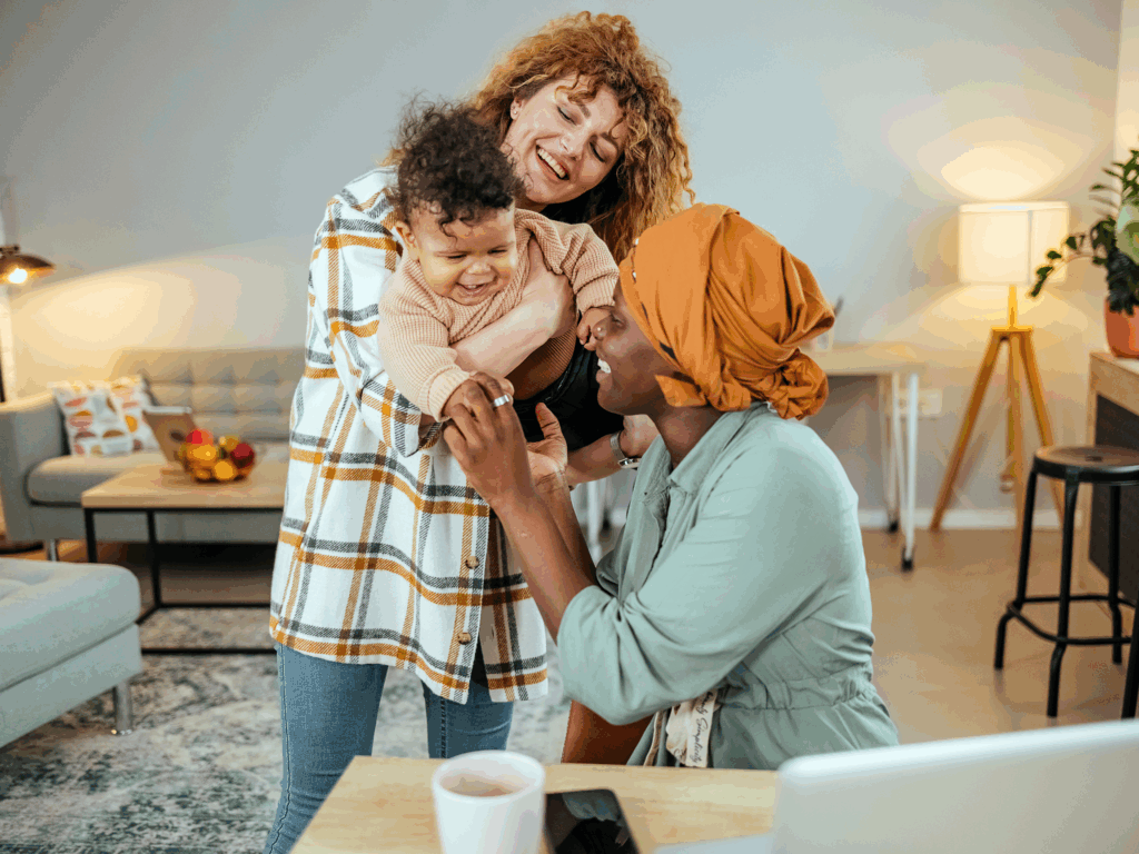 Two moms smiling with their child in a cozy living room, preparing for a move or home sale
